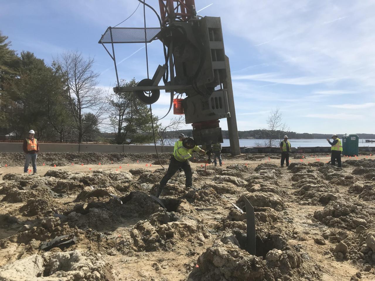 Construction crew coordinating foundation work beside a roadway